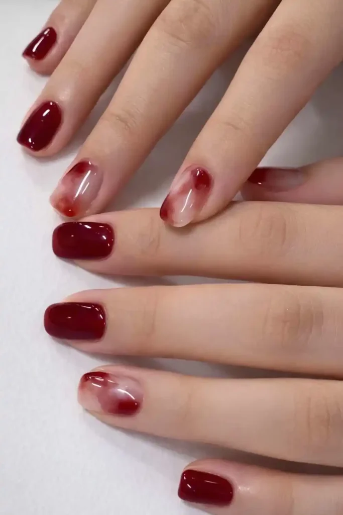 Deep Red Nails With Accent Marble Art for an Elegant Finish